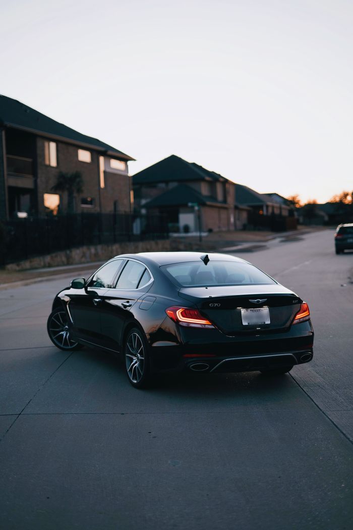 A sleek black luxury sedan parked on a quiet residential street during twilight.